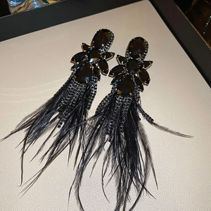 Detail of dark floral earrings featuring black crystal stones and long feather tassels