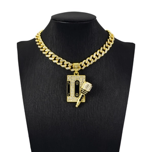 Close-up of golden iced-out Cuban chain with cassette and microphone pendants on bust