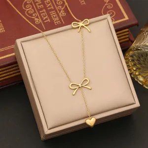 Detail of a golden bow necklace with heart pendant on a champagne jewelry display box