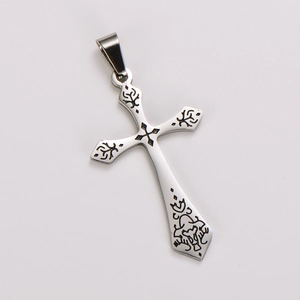 Macro shot of silver retro cross pendant with detailed black floral engravings and textures