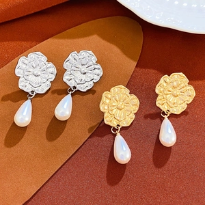 Macro detail of floral pearl drop earrings in vintage gold and silver embossed finishes