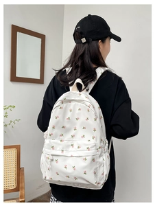 Floral print backpack featuring small pink flowers on a white fabric shown from behind