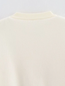 Primer plano del cuello redondo acanalado y la textura de punto fino de este top crema