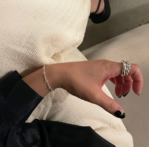 Detail of S925 sterling silver twisted chain bracelet and matching rings on model hand