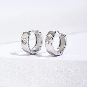 Macro view of wide hoop earrings with micro-inlaid heart zircon stones in silver