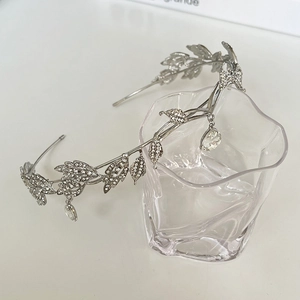 Detailed view of silver crystal bridal crown with leaf motifs and water drop pendants