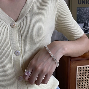 Detailed view of silver chain bracelet and heart-shaped pink zircon ring on model's hand