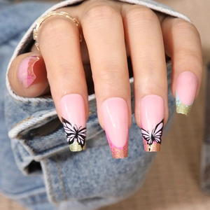Close-up of long coffin fake nails featuring pink base with black butterflies and gold glitter
