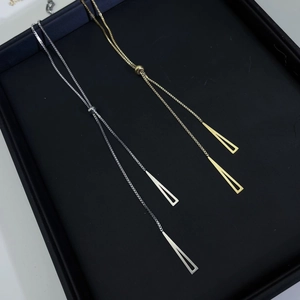 Detailed view of adjustable gold and silver long triangle pendants on black velvet tray