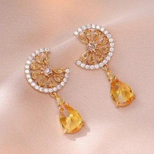 Close-up of elegant flower earrings with yellow pear-cut cubic zirconia on champagne silk