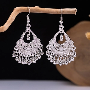 Detail of ethnic silver drop earrings with floral hollow carvings and beaded tassels