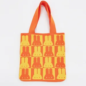 Close-up of thick knit texture with orange rabbit jacquard pattern on checkerboard tote