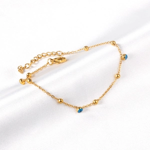 Detailed close-up of golden evil eye bracelet on white satin with adjustable clasp