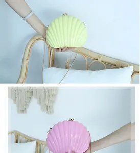 Detail of shell-shaped acrylic clutch bags in pastel green and pink with gold chain