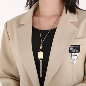 Close-up of a model wearing a long 18K gold geometric pendant necklace with tassels