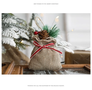 Detail of Christmas burlap gift bag with pine cones, berries and wooden base support