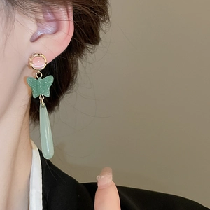 Elegant long drop cat eye stone butterfly earrings worn by a model in soft lighting