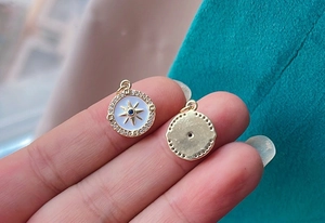 Detailed close-up of double-sided gold compass pendant with blue gemstone and zircons