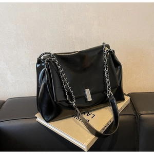 Detail of glossy black oil wax leather texture with silver chain strap and metal clasp