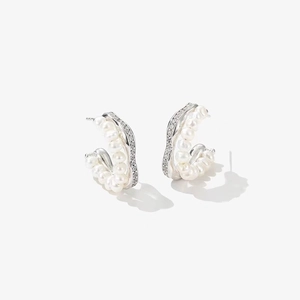 Detail shot of elegant pearl earrings with sparkling zircon borders on white background