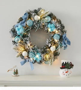 Detail of blue and white Christmas wreath with LED lights and festive ornaments on wall