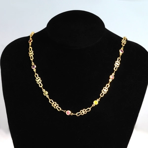 Detailed view of hollow patterned gold chain with colorful pink and yellow zircon gems