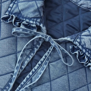 Quilted blue bomber jacket with diamond pattern, ruffled collar and bow tie closure