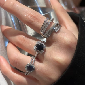 Close-up of silver rings with navy blue oval gemstones and zircon pave on female fingers