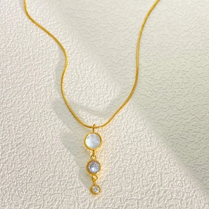 Macro shot of gold tassel necklace with white shell, blue zircon and crystal charms