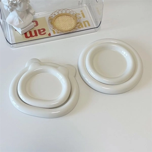 Minimalist white ceramic round and bear-shaped dessert plates on a white table