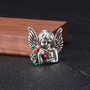 Detailed close-up of a vintage angel brooch holding red flowers and sparkling crystals