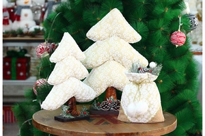 Detail of fabric Christmas tree with snowflake patterns and pine cone ornaments on wood