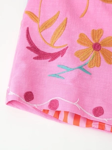 Close-up of pink linen cardigan with floral embroidery and orange striped lining details