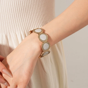 Close-up of vintage gold circular link bracelet with white marble stone inlays and texture