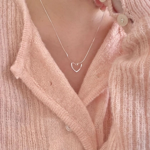 Minimalist 925 sterling silver heart pendant necklace on a model wearing pink cardigan