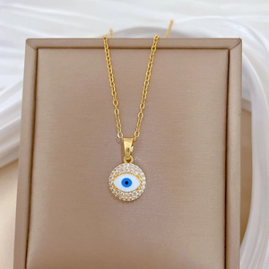 Golden Evil Eye pendant necklace with blue crystals on a beige jewelry display stand