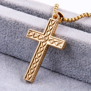 Detailed close-up of golden stainless steel cross pendant with hollow heart patterns