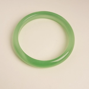 Detailed top view of a translucent green cat's eye stone bangle with a smooth finish