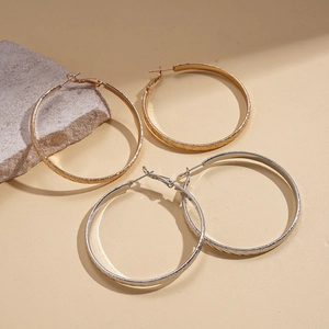 Textured gold and silver hoop earrings set displayed on a natural stone background
