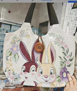 Detail von bestickten Kaninchen und Blumen auf Canvas-Tasche mit großem Holzknopfverschluss