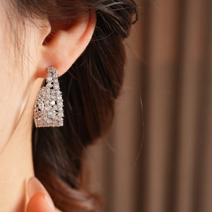 Primo piano di eleganti orecchini a U in argento con zirconi scintillanti sul modello