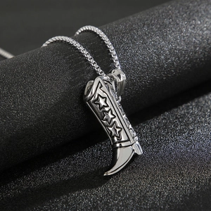 Detailed view of a silver titanium steel boot pendant with star relief on a black background