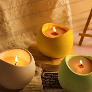 Dettaglio di candele profumate in ceramica opaca in tonalità gialle e verdi