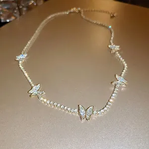 Elegant gold butterfly necklace with shimmering crystals on a textured warm background