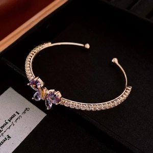 Gros plan d'un bracelet papillon doré avec zircons violets dans un écrin noir