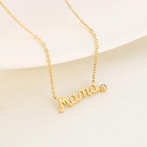 Detail of gold Mama letter necklace with a sparkling round zircon on beige fabric
