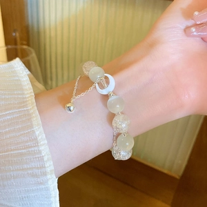 Close-up of cat eye stone bracelet with moon pendant on wrist in soft lighting