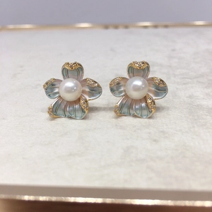 Detailed macro view of 18K gold floral earrings with freshwater pearl and purple enamel