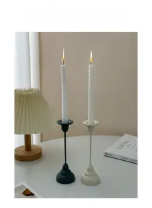 Detail of matte black and cream metal candle holders with white spiral candles lit