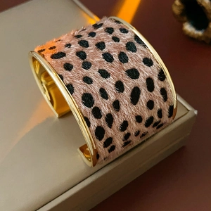 Detail of leopard print faux fur cuff bracelet with golden metallic edges in a luxury style